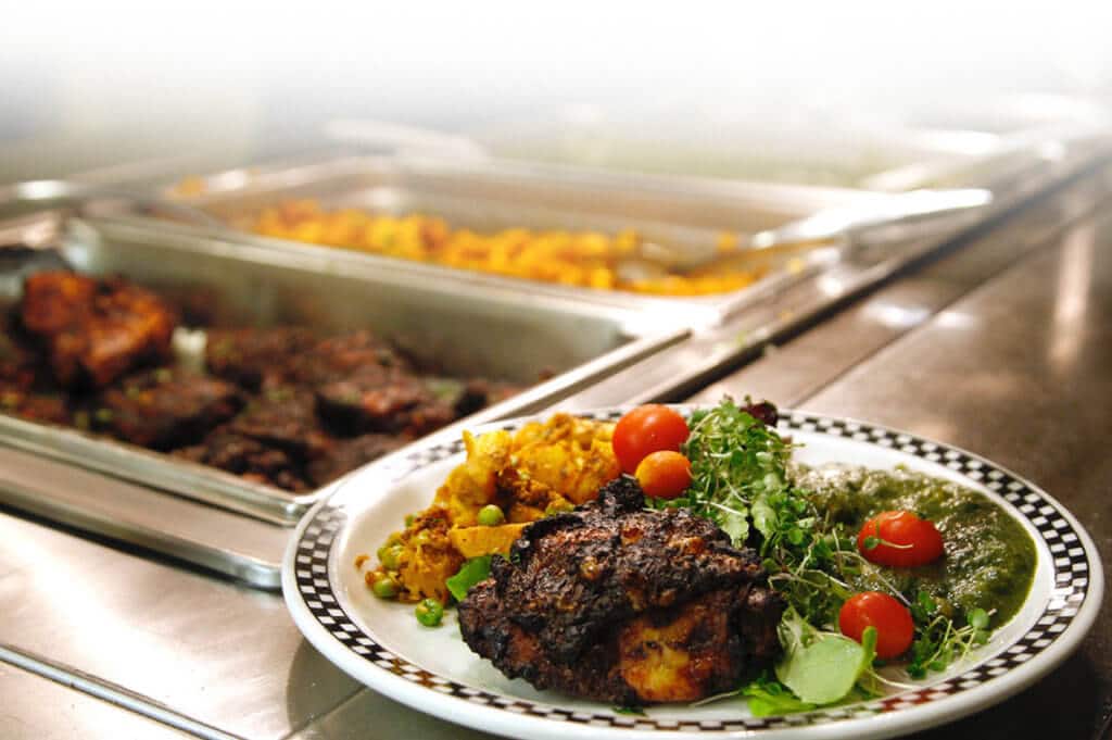 A healthy meal with meat and vegetable sides sits on a buffet counter