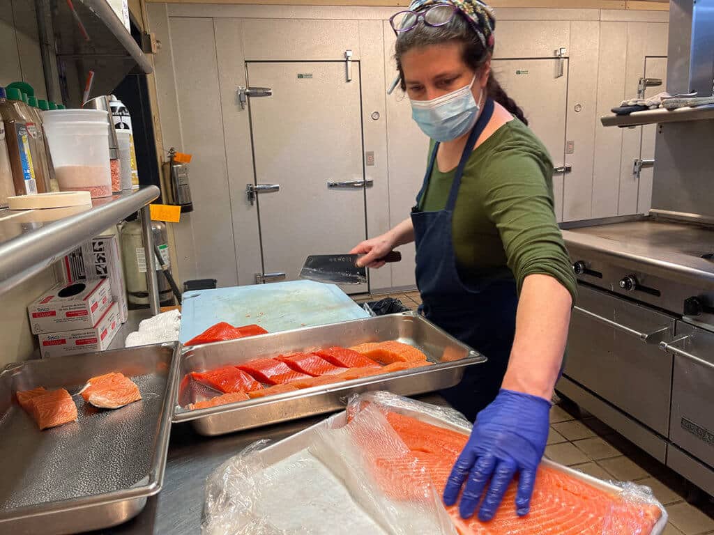 gloved person working with raw salmon in the kitchen
