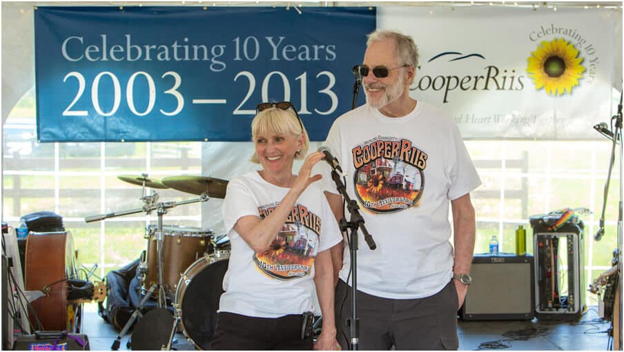 Don and Lisbeth Cooper stand in front of a microphone at a 10 year anniversary celebration