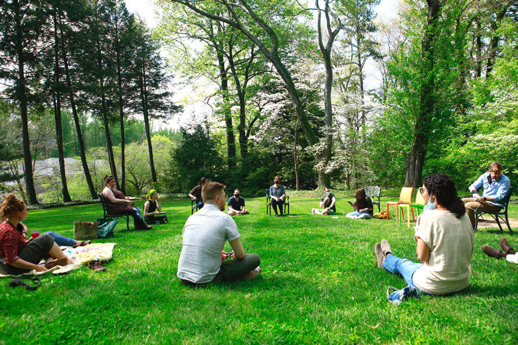 a circle of people sitting on the lawn