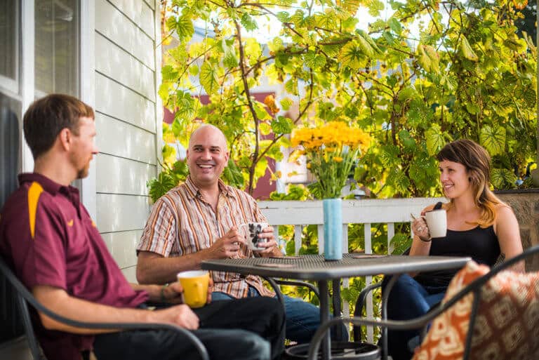 three people around a table with mugs