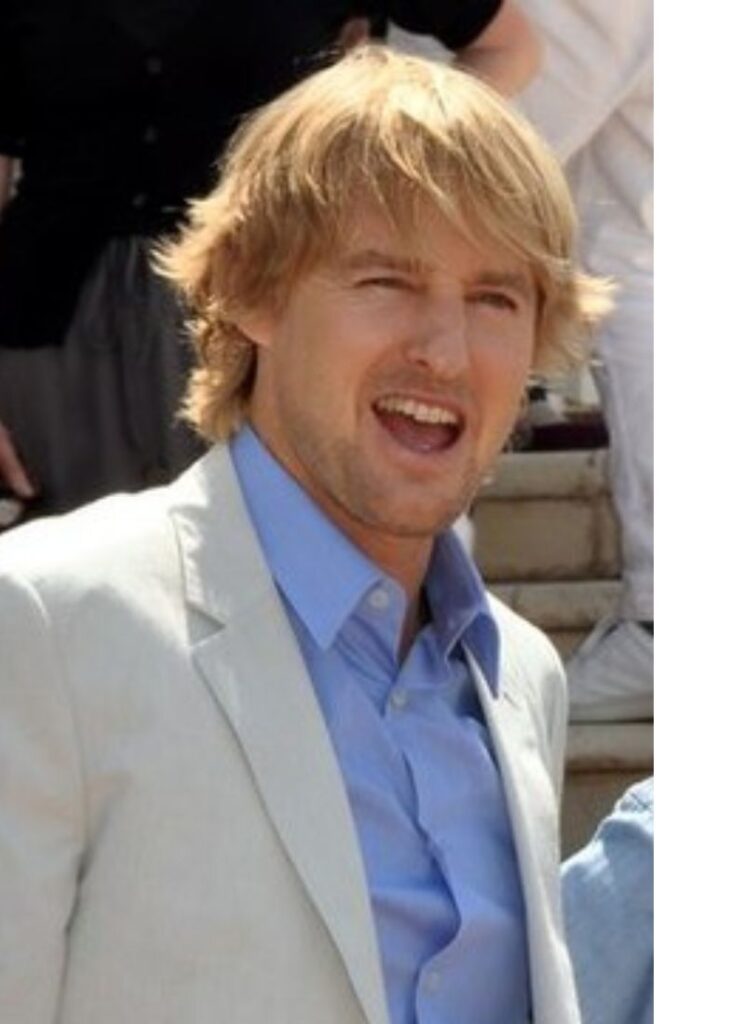 owen wilson at cannes film festival in 2011, smiling, wearing white suit and blue shirt
