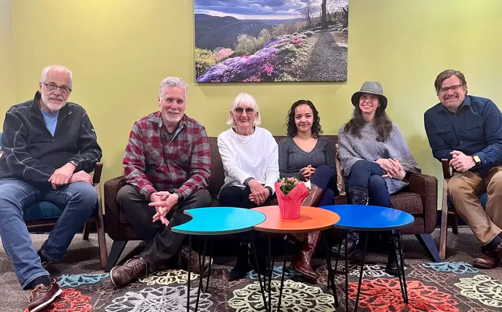 Senior staff sits smiling on a couch at the day program