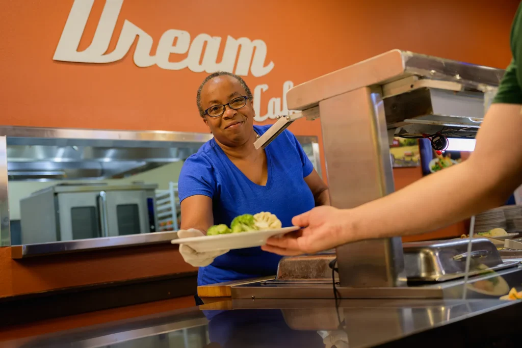 Sous chef serves a delicious meal to a resident