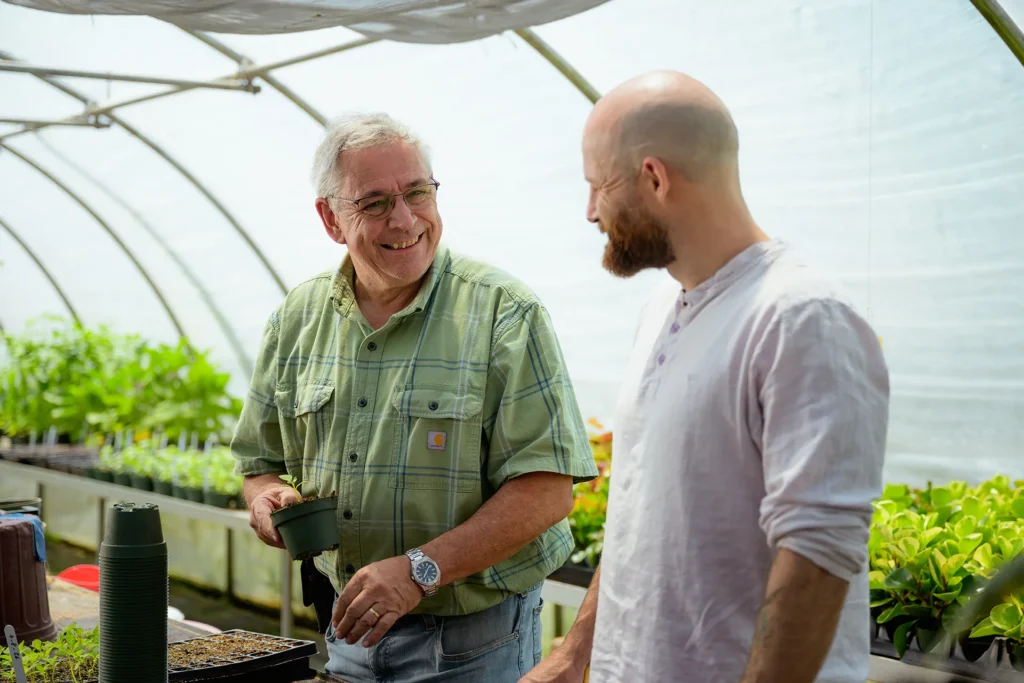 Two men work together in the greenhouse at CooperRiis