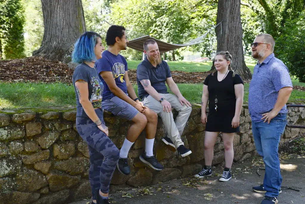 Group chatting and sitting on a stone wall at a residential mental health community in Asheville NC